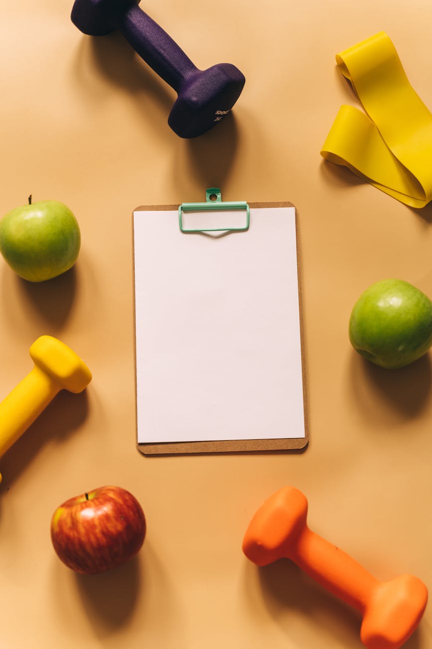overhead shot of dumbbells apples and a clipboard